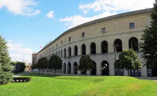 A stadium encircled by lush green grass and trees